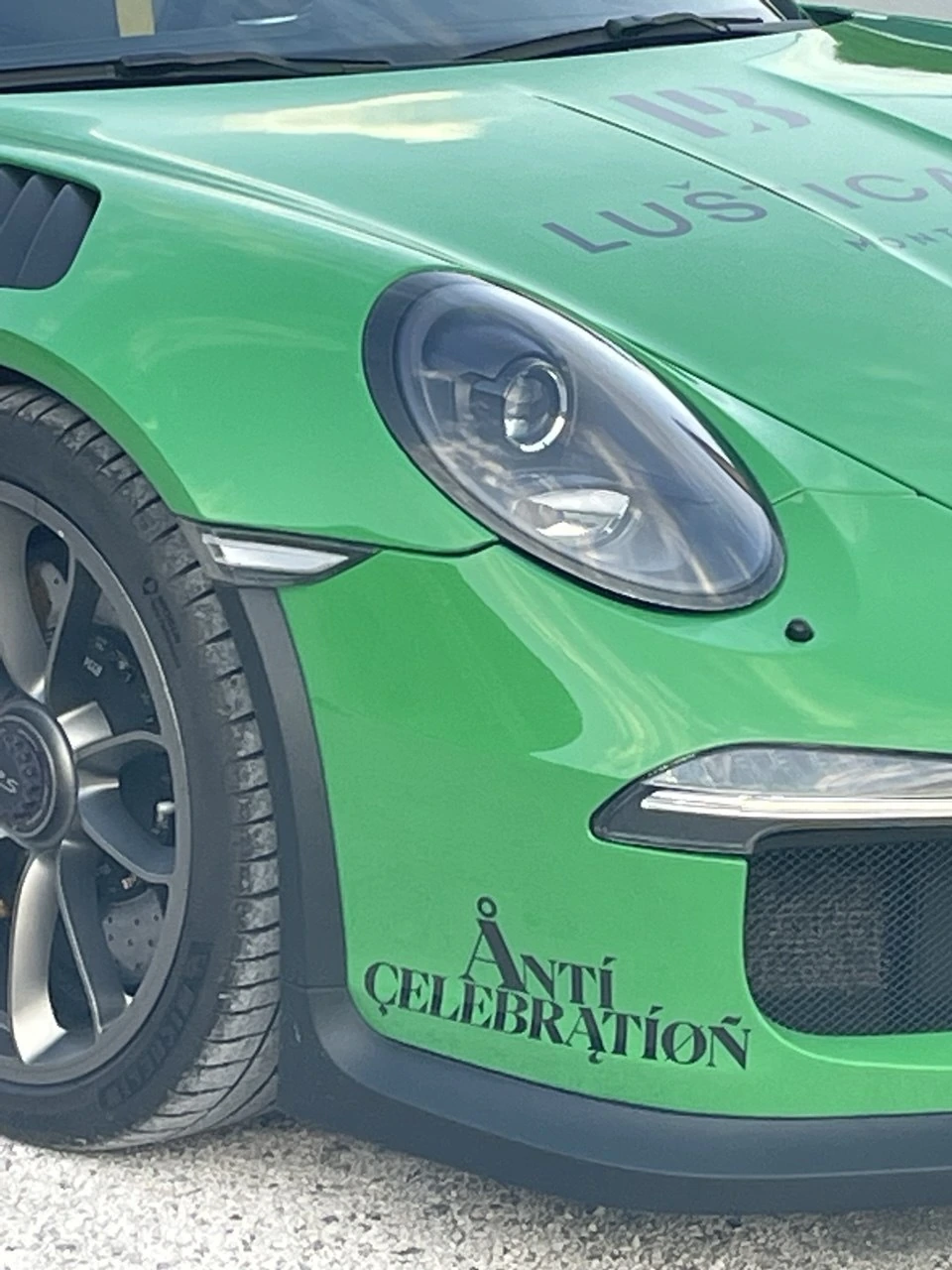 A green Porsche 911 with the Anticelebration logo